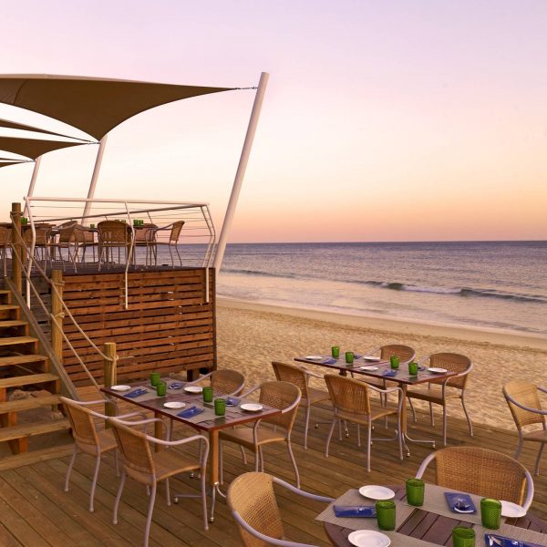 View of the beach and dining at dusk at Pine Cliffs, A Luxury Collection Resort in Algarve in Portugal